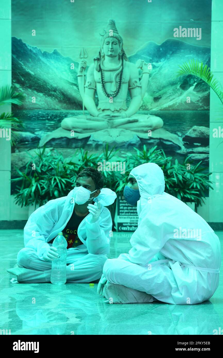 New Delhi, India. 04th May, 2021. Health workers wearing PPE suits take a break as they cremate bodies of  COVID-19 victims at a crematorium, in New Delhi, India, Tuesday, May 4, 2021.  More than 20 million Indians have been infected with the coronavirus as it continues to spread with 3,500 deaths in the past 24 hours. Credit: UPI/Alamy Live News Stock Photo