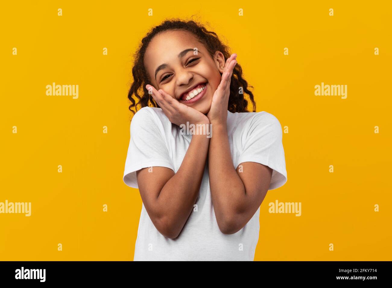 Cute Joyful African American Girl Touching Cheeks Stock Photo