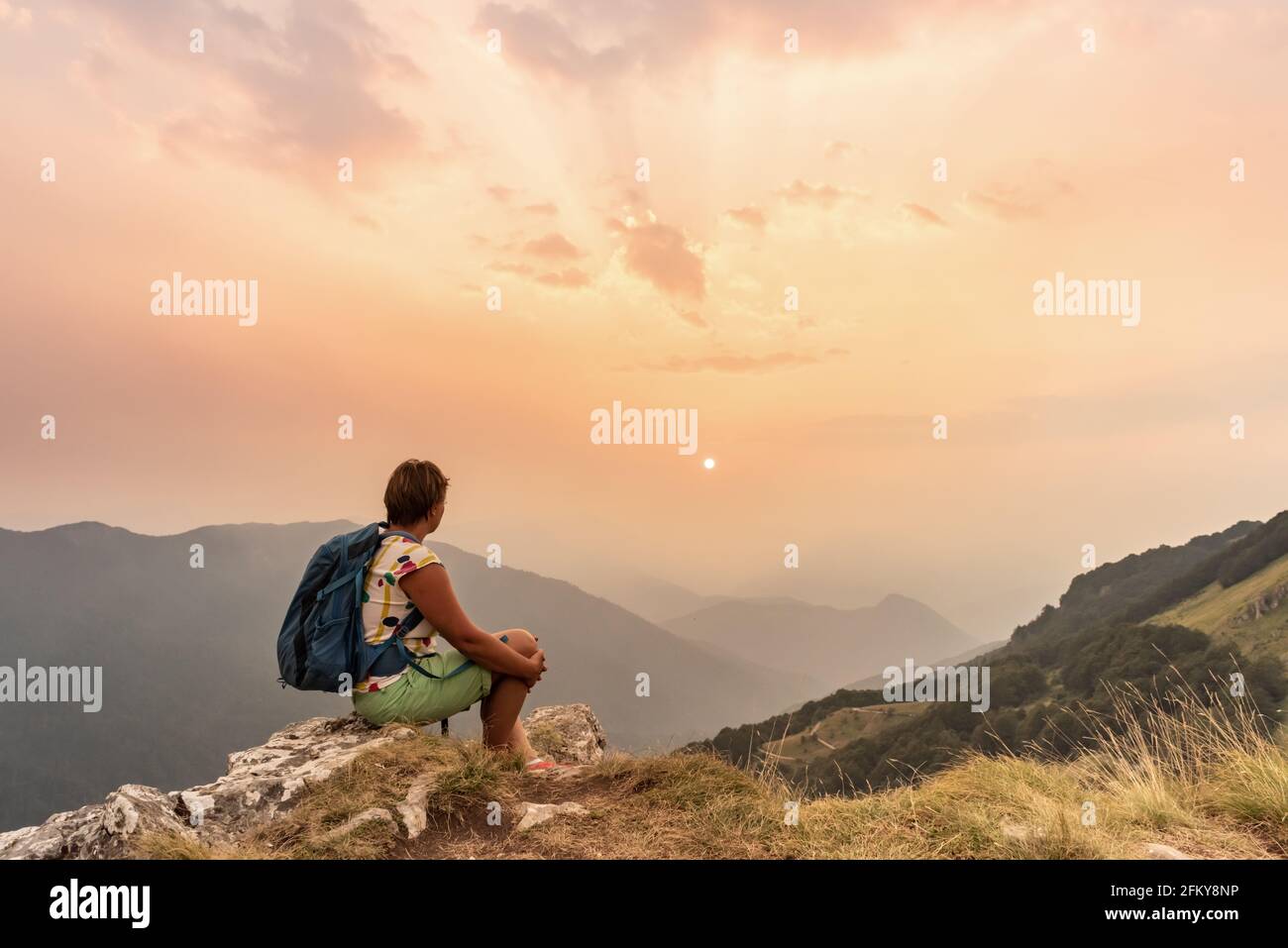 One tourist with backpacks enjoying sunset on top of a mountain Stock ...