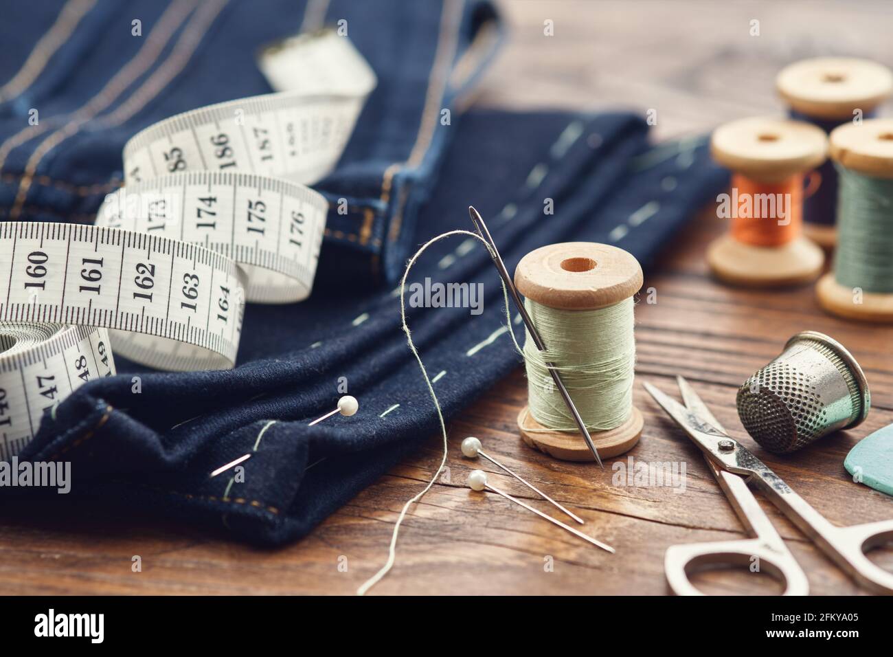 Shortening jeans. Measuring tape, scissors, spools of thread, thimble