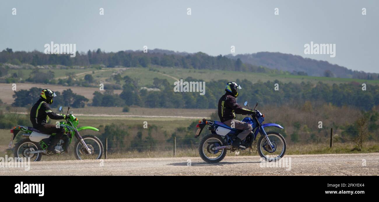 two off-road motorcyclists kick up dust as they ride over a stone track on Salisbury Plan military training area Stock Photo