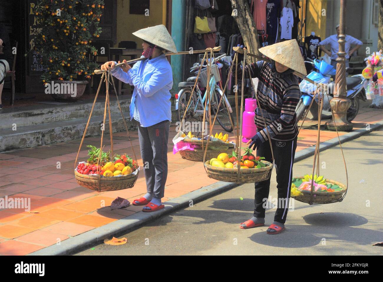 Street fruit sellers with traditional carrying baskets, Hoi An, Vietnam
