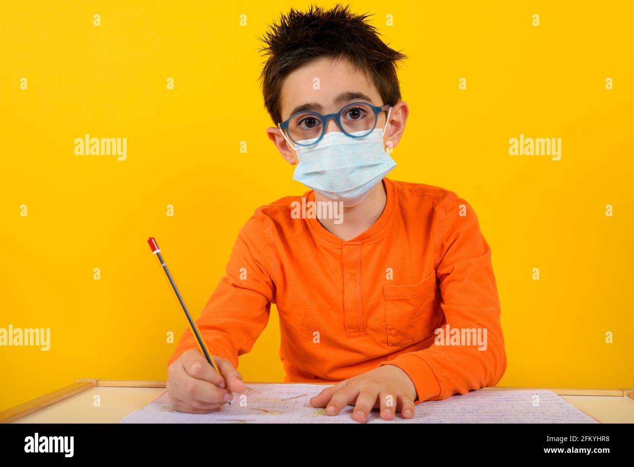 Child at school with face mask for covid-19 coronavirus. yellow background Stock Photo
