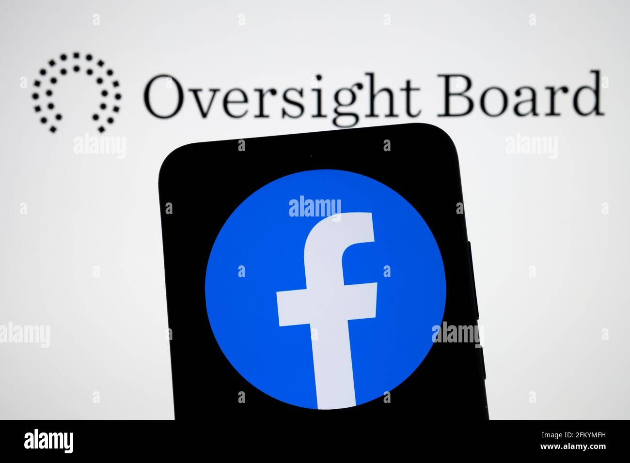 Facebook Oversight Board logo on the blurred background screen and Facebook app logo on the smartphone on the front. Stafford, United Kingdom, May 4, Stock Photo