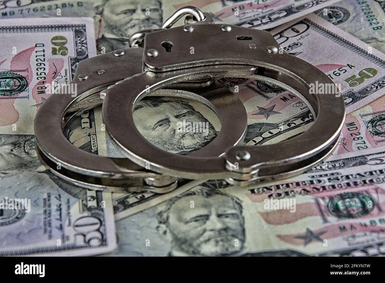 Handcuffs on dollars in close-up on a dollar-covered screen Stock Photo
