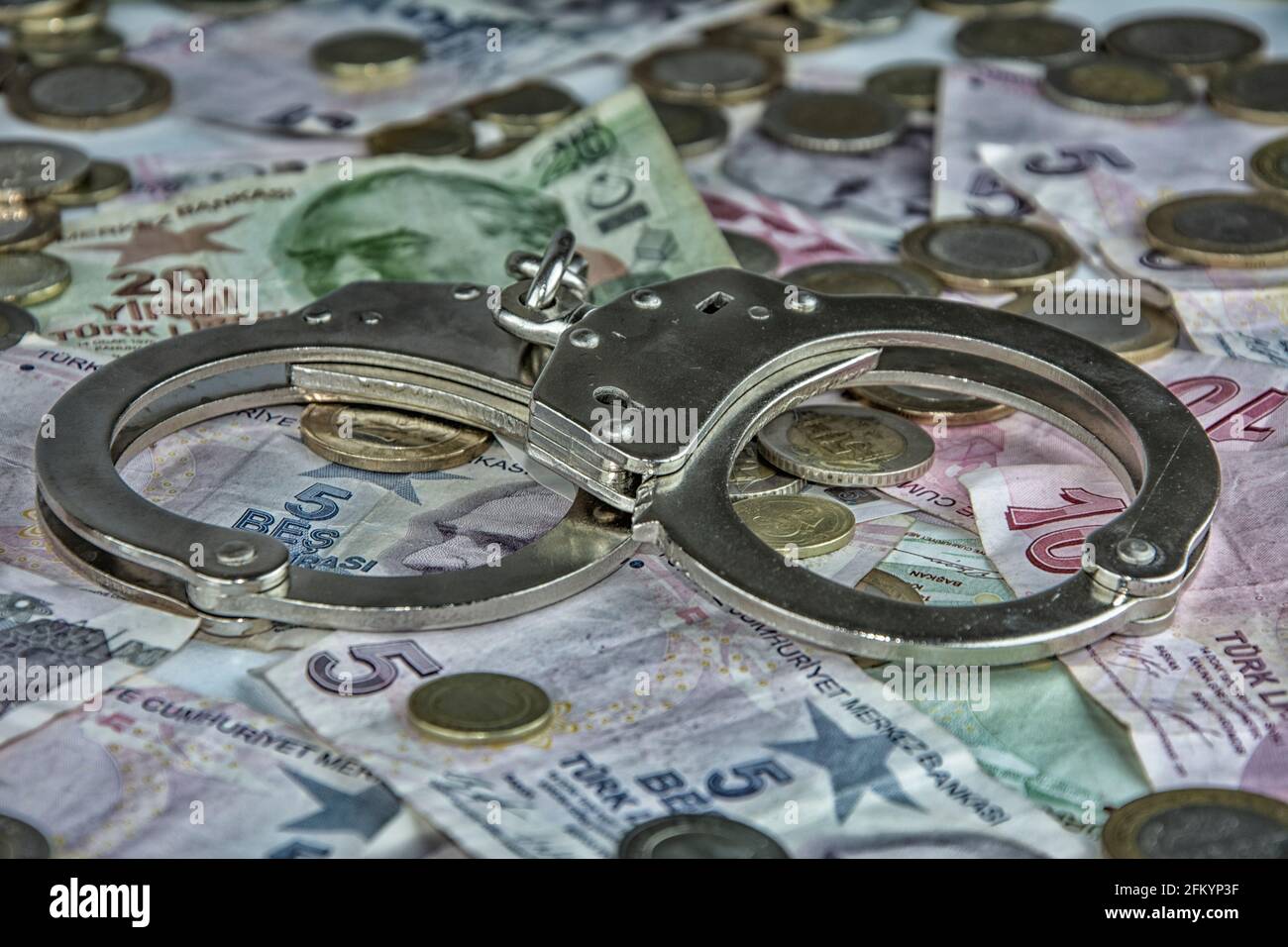Handcuffs on the paper money in close-up on the screen covered with paper money Stock Photo