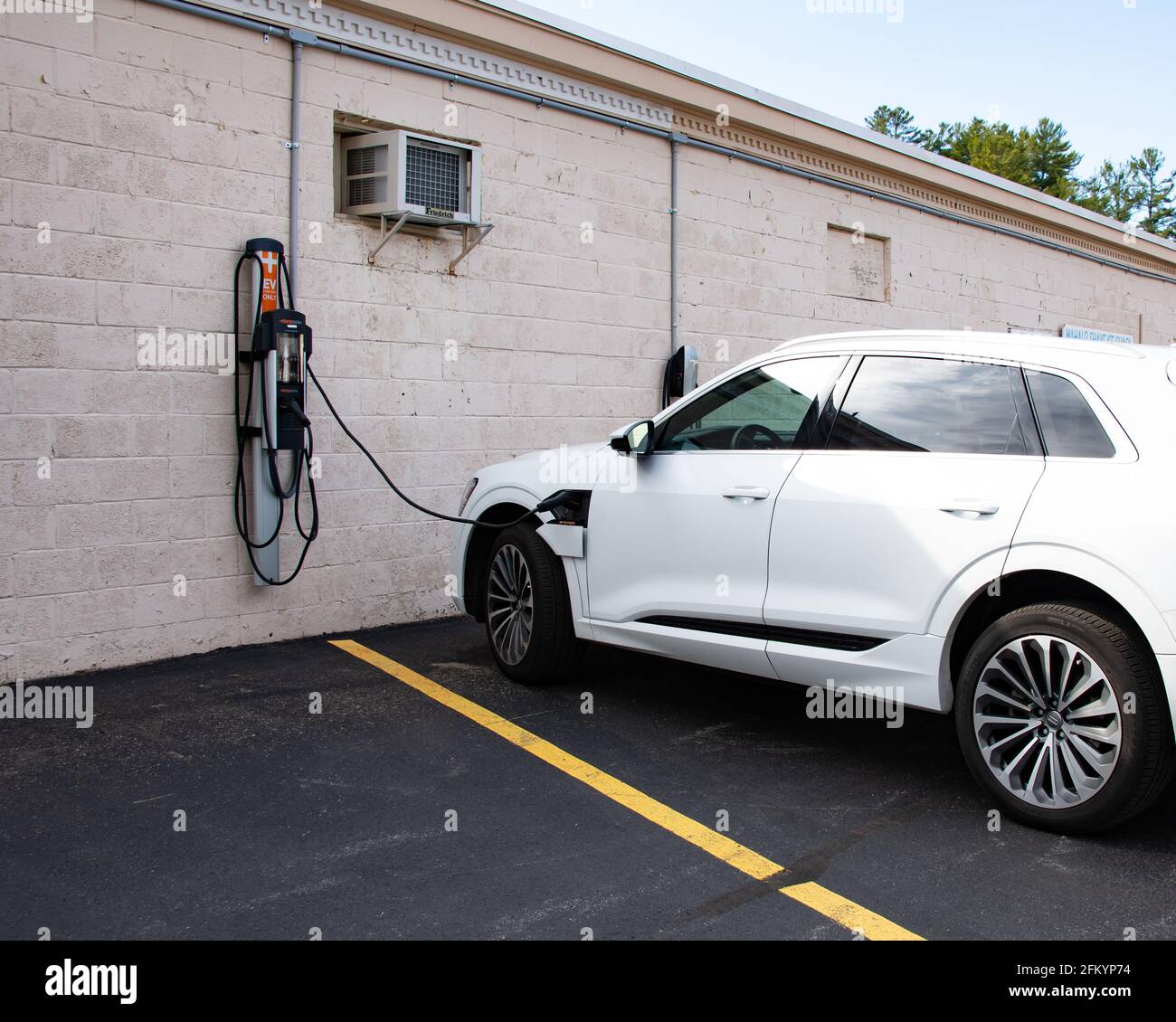 A white Audi E-tron getting a battery charge at an EV charging station in Speculator, NY USA Stock Photo