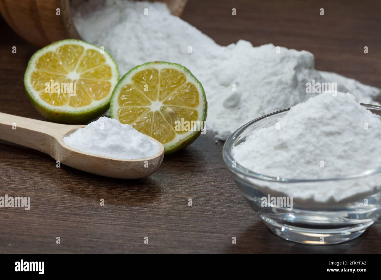 Baking soda sodium bicarbonate and lemon; on dark wooden background