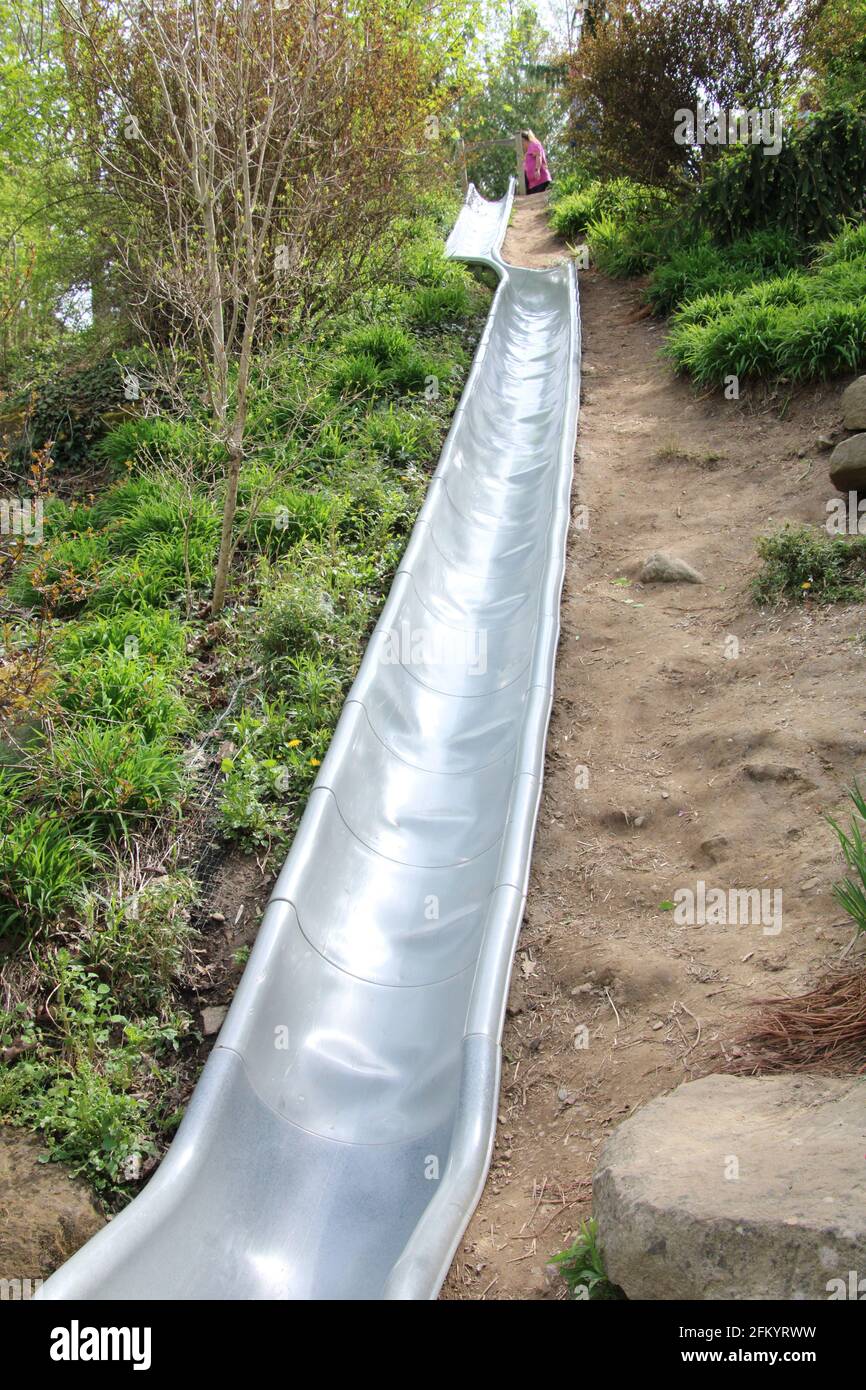 Long Slide, with bend half-way down, going down hill side Stock Photo