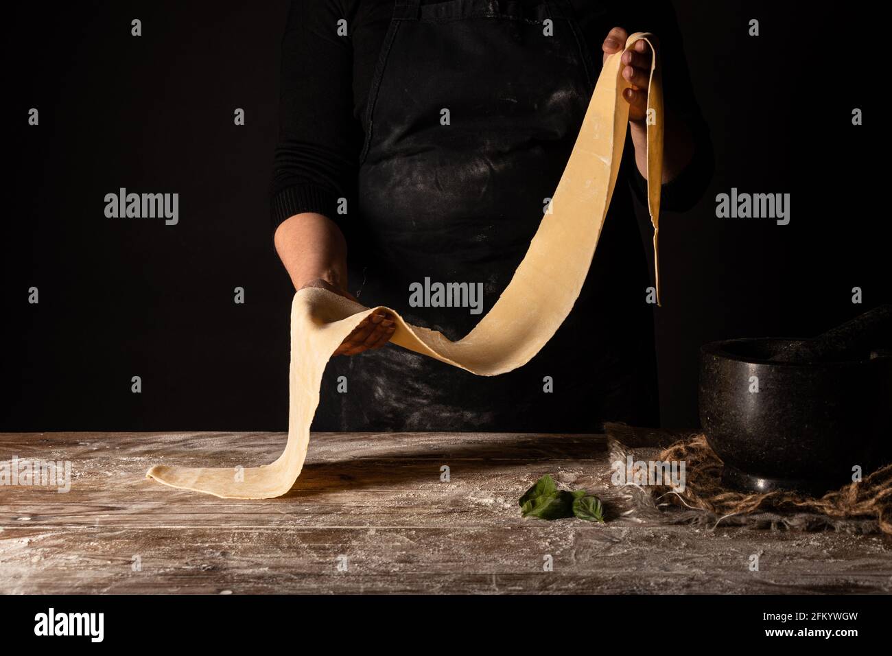 Lady standing behind table with pasta in hands Stock Photo