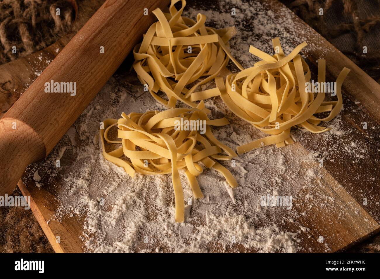 Pasta nests on floured board with rolling pin Stock Photo - Alamy
