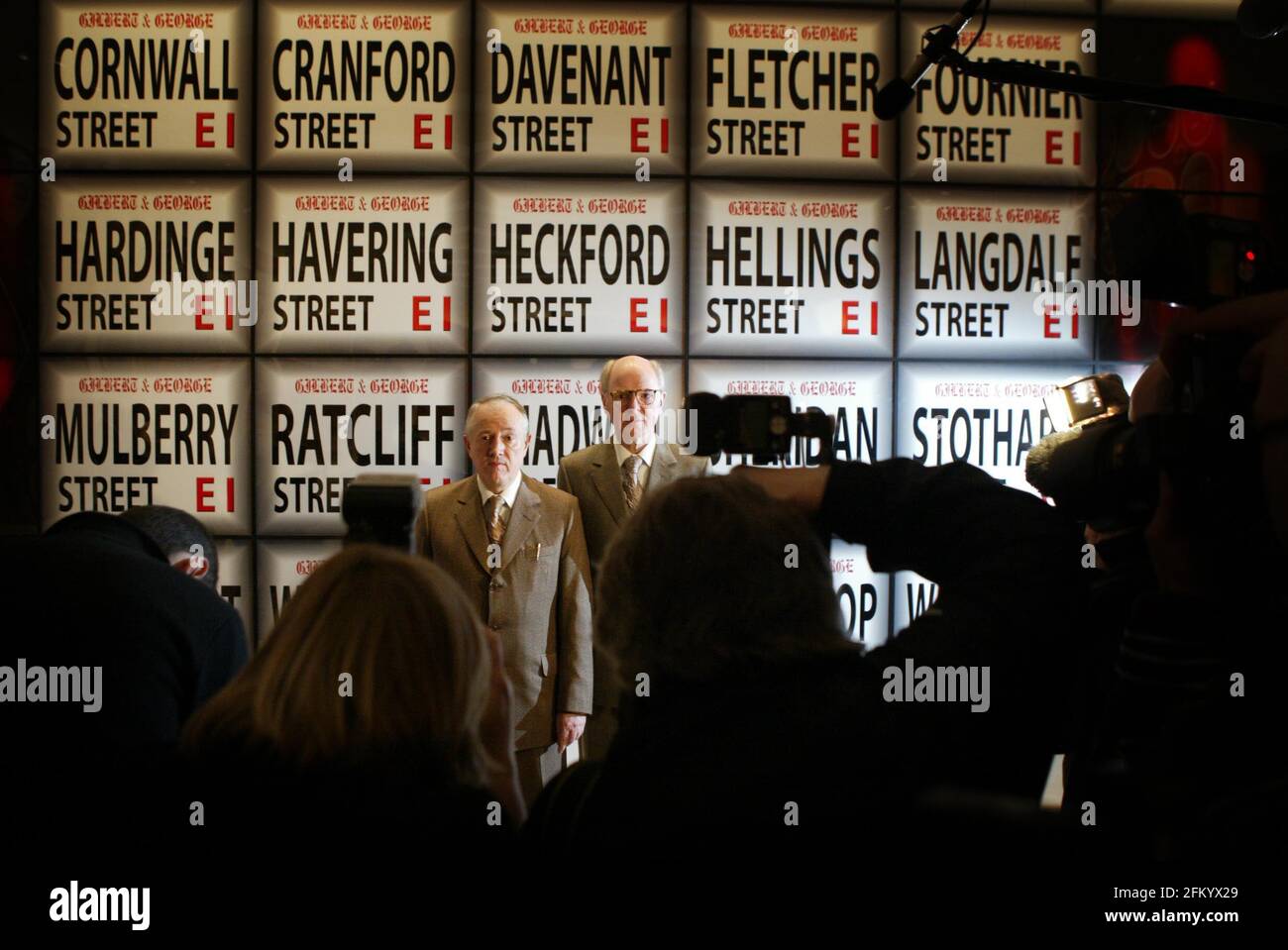 Gilbert Proesch (L) and George Passmore, known as 'Gilbert and George,' are surrounded by journalists in front of their artwork Three Dozen Streets - 2003 at The Tate Modern in London  pic David Sandison Stock Photo