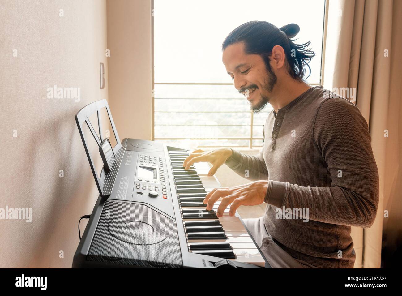 Young latin man learning to play piano at home during quarantine Stock  Photo - Alamy