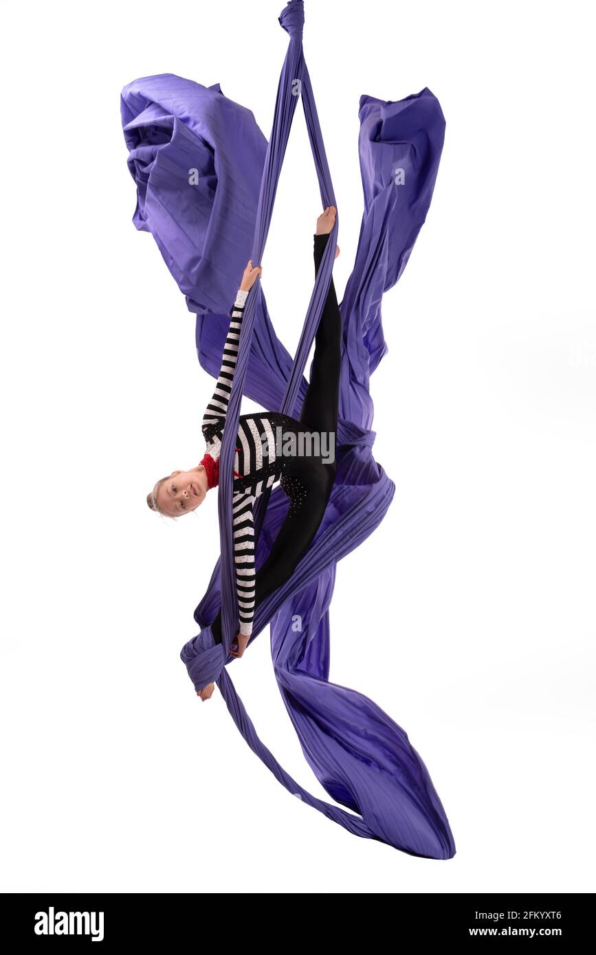 Flexible girl doing aerial silks trick on fabric Stock Photo