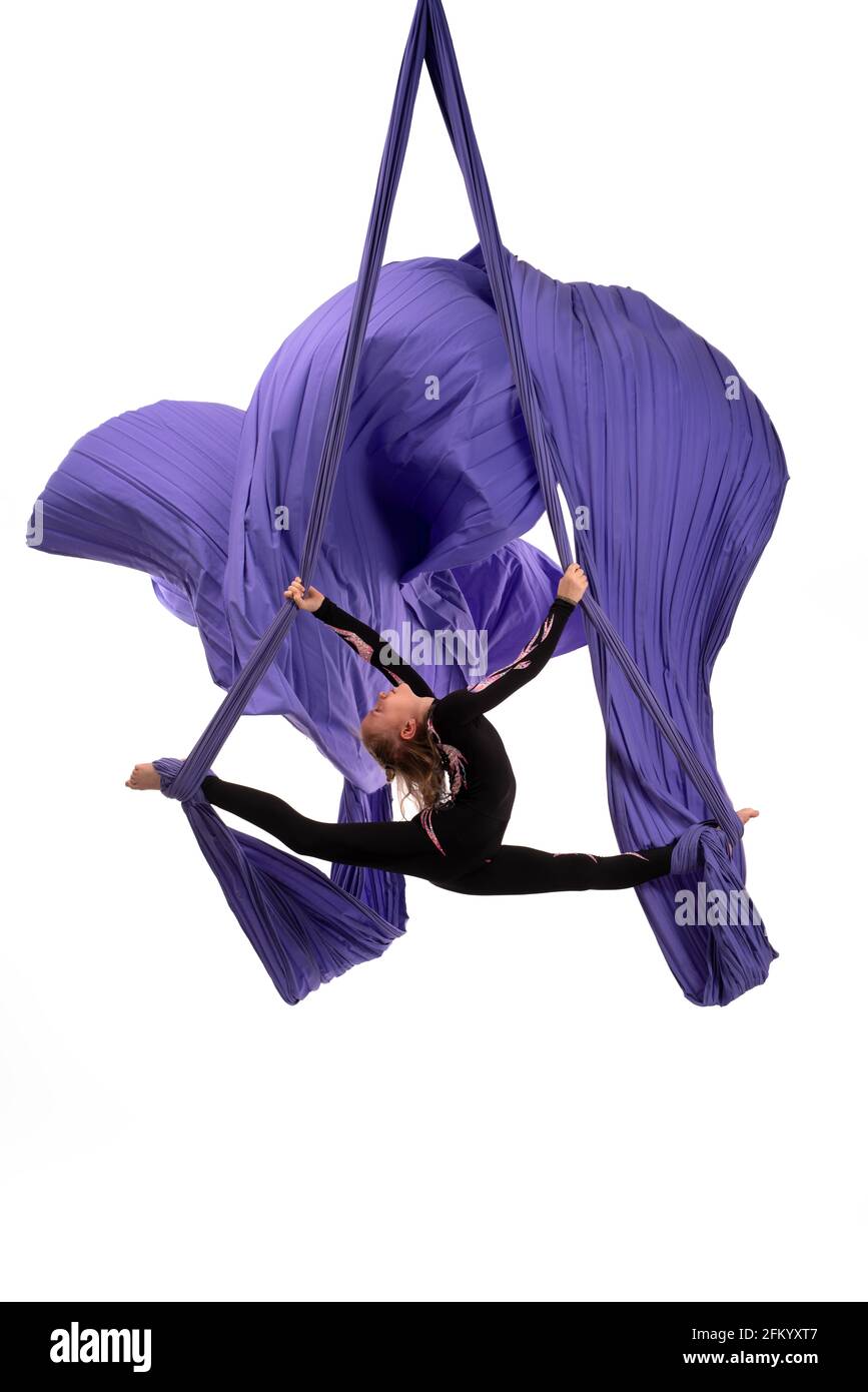 Flexible woman doing aerial silks trick on fabric Stock Photo