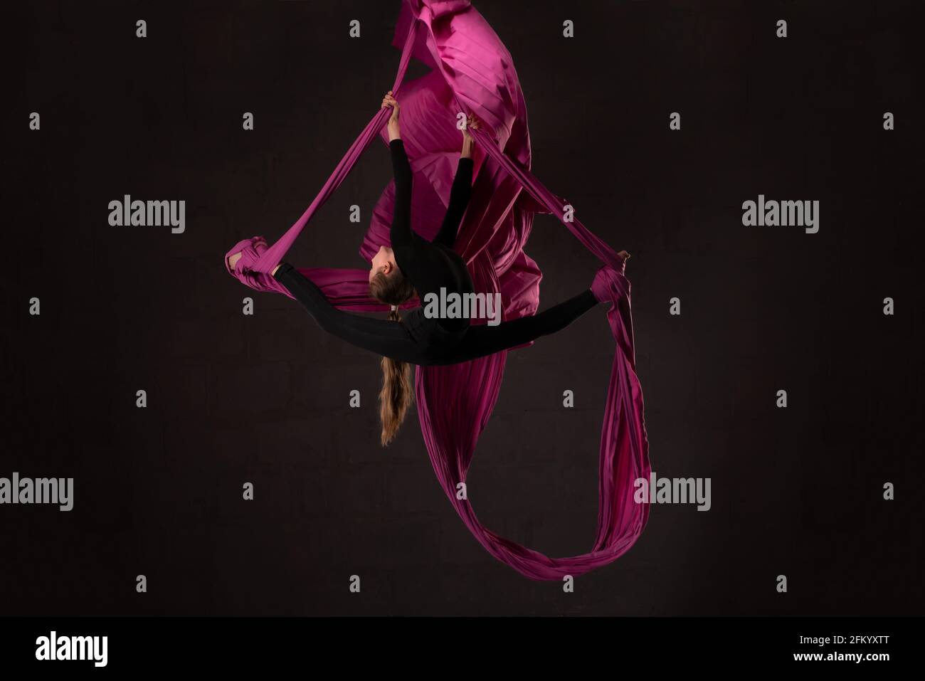 Flexible teen doing aerial silks trick on fabric Stock Photo