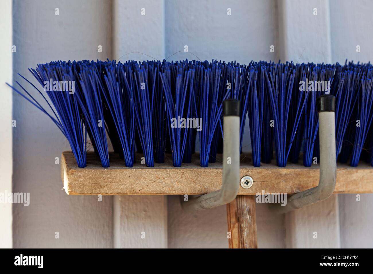 part of a blue broom hanging on a wall Stock Photo