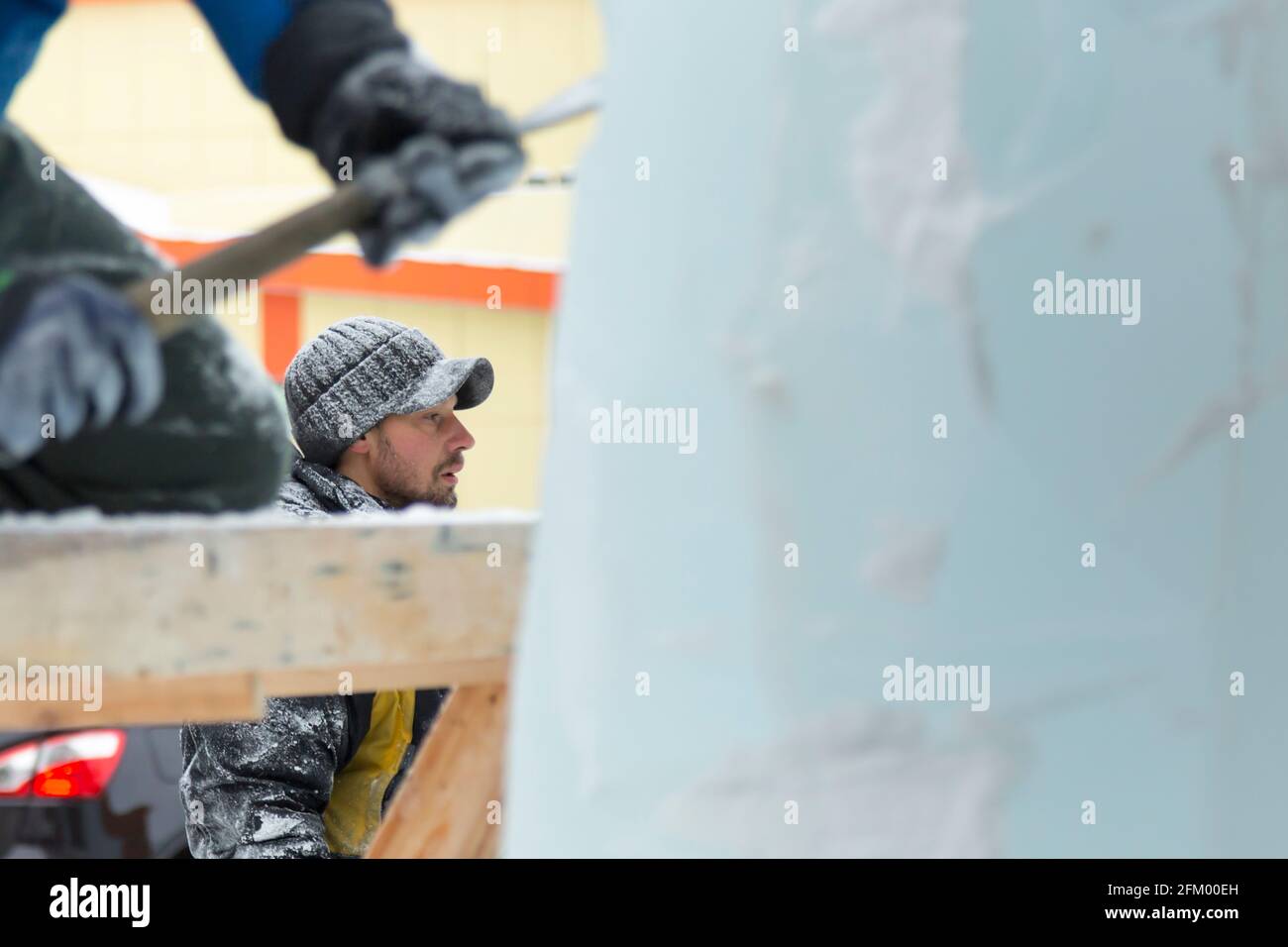 The sculptor cuts an ice figure out of an ice block with a chisel Stock ...