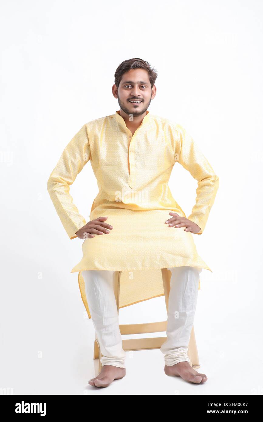 Young indian man in tradition wear and sitting on white background ...