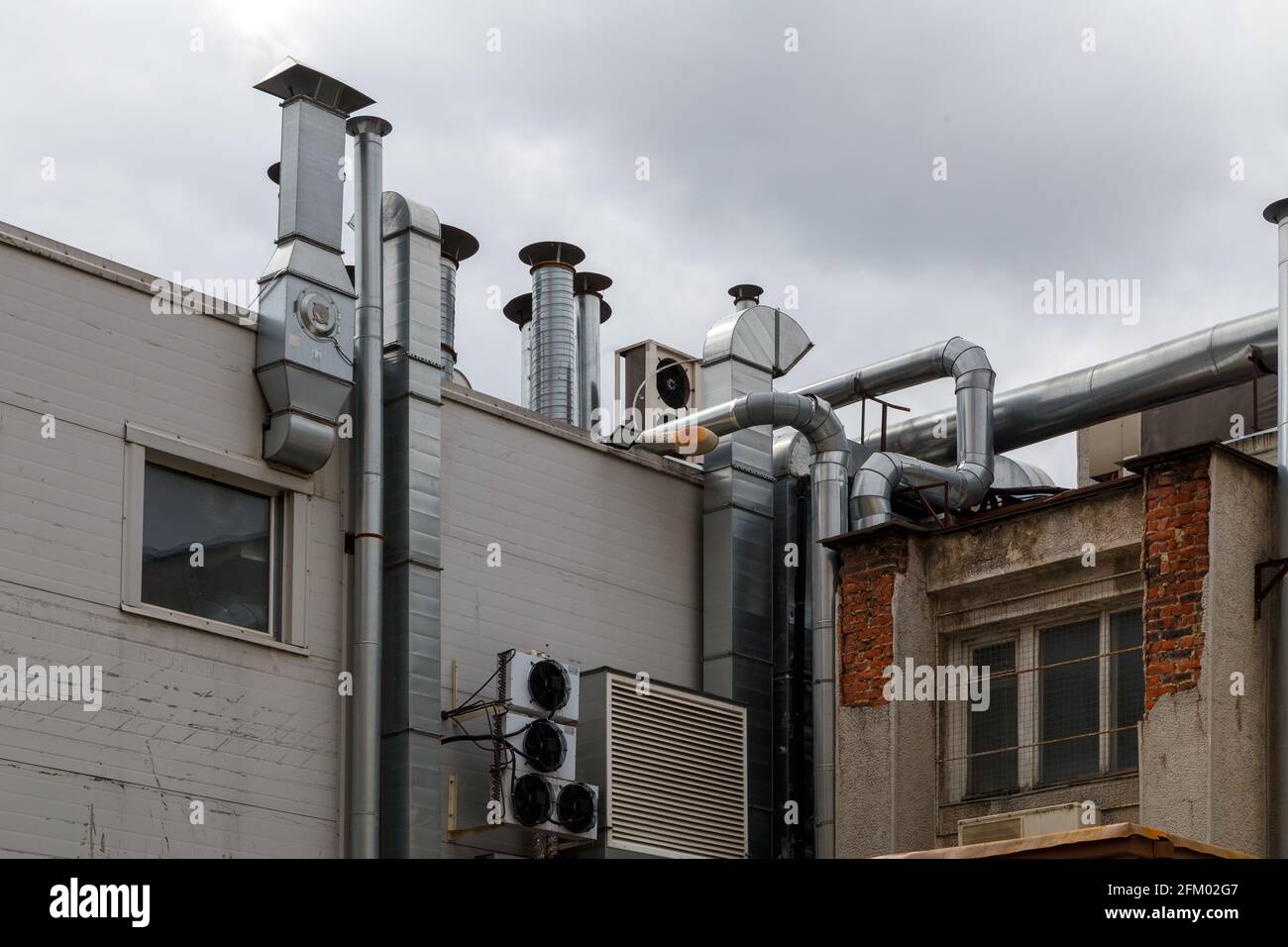 old outdoor ventilation air ducts and air conditioners outside of back wall of cafe kitchen