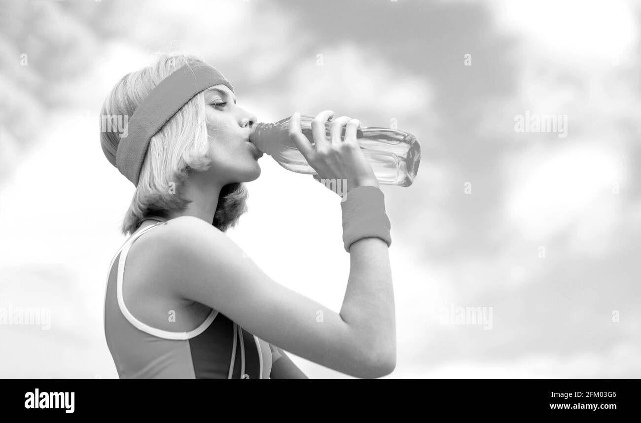 Drinking during sport. Young woman drinking water after run. Woman in sports wear is holding a bottle of water. Sports girl drinks water from a bottle Stock Photo