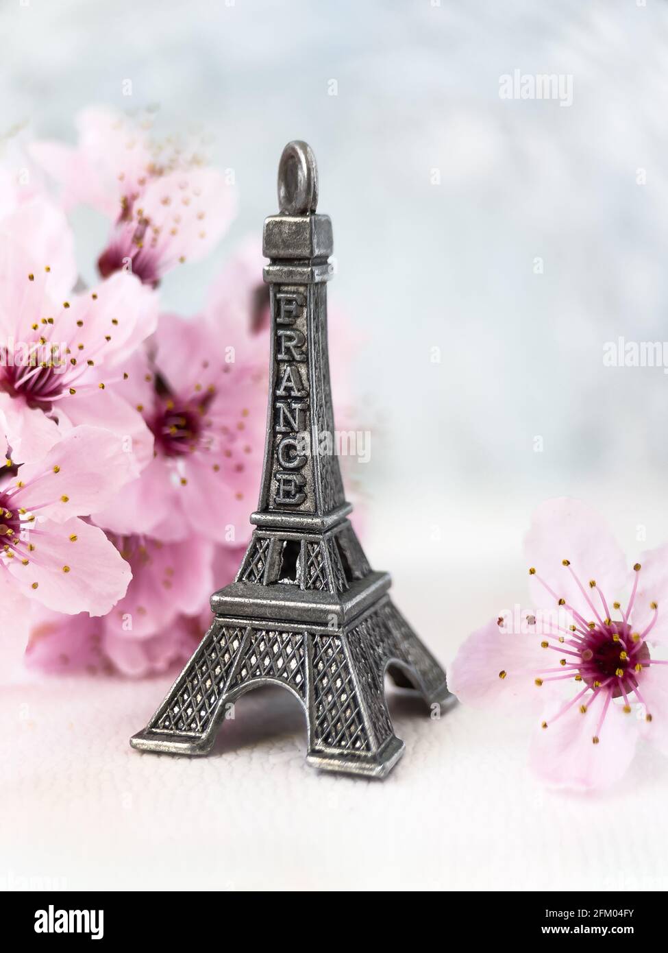 Miniature of Eiffel Tower with blooming cherry blossom. Eiffel Tower toy with spring cherry flowers. Stock Photo