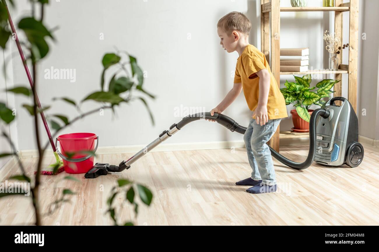A little child helps his parents in housework, cleaning the floor using ...
