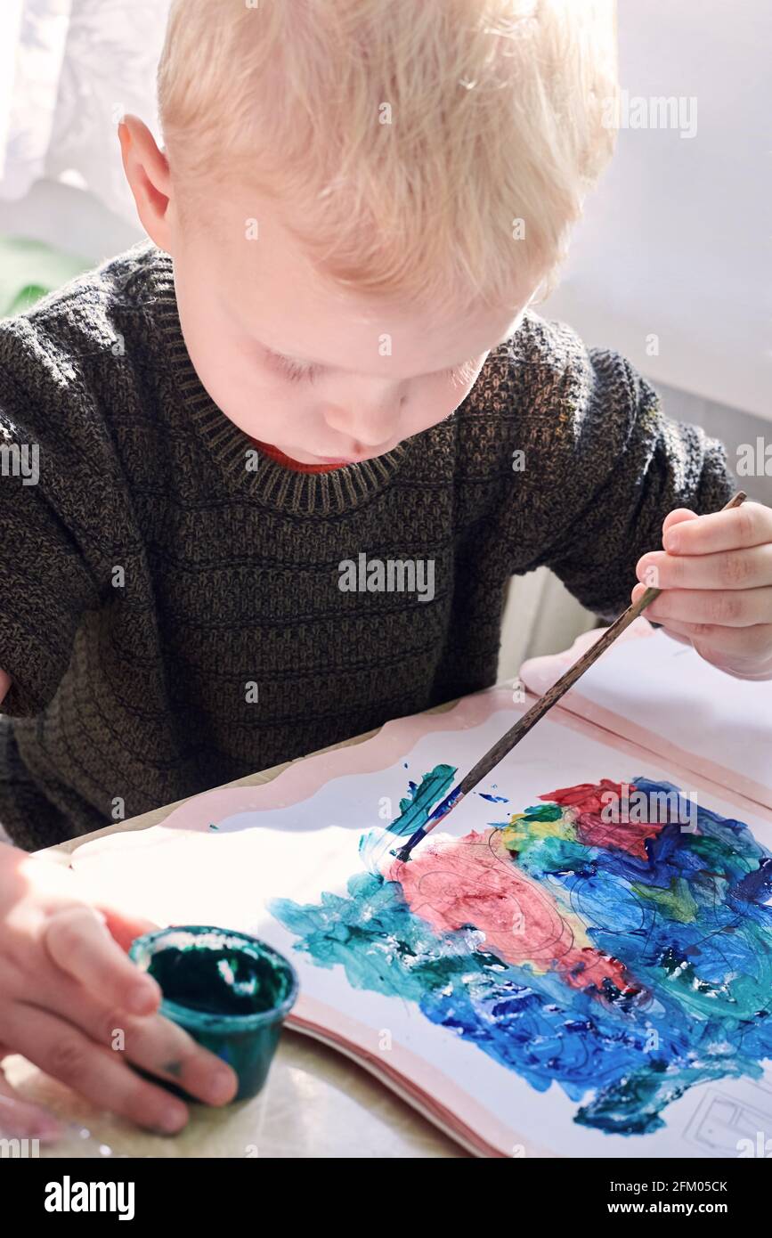 A three-year-old boy paints with gouache coloring, leisure and child ...