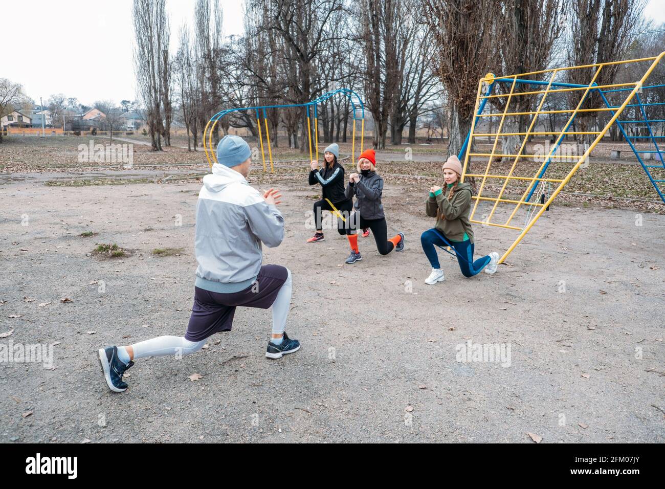 Group fitness workout classes outdoors. Socially Distant Outdoor Workout Classes in public parks. Three women and man training together in the public Stock Photo
