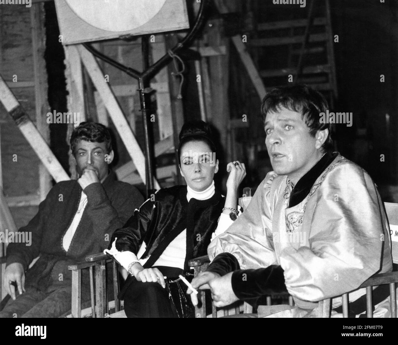 PETER O'TOOLE and RICHARD BURTON with Set Visitor ELIZABETH TAYLOR on set candid during filming of BECKET 1964 director PETER GLENVILLE play Jean Anouilh and Lucienne Hill screenplay Edward Anhalt costume design Margaret Furse producer Hal B. Wallis  Wallis-Hazen A Paramount Film Service & Keep Films Co-Production / Paramount Pictures Stock Photo