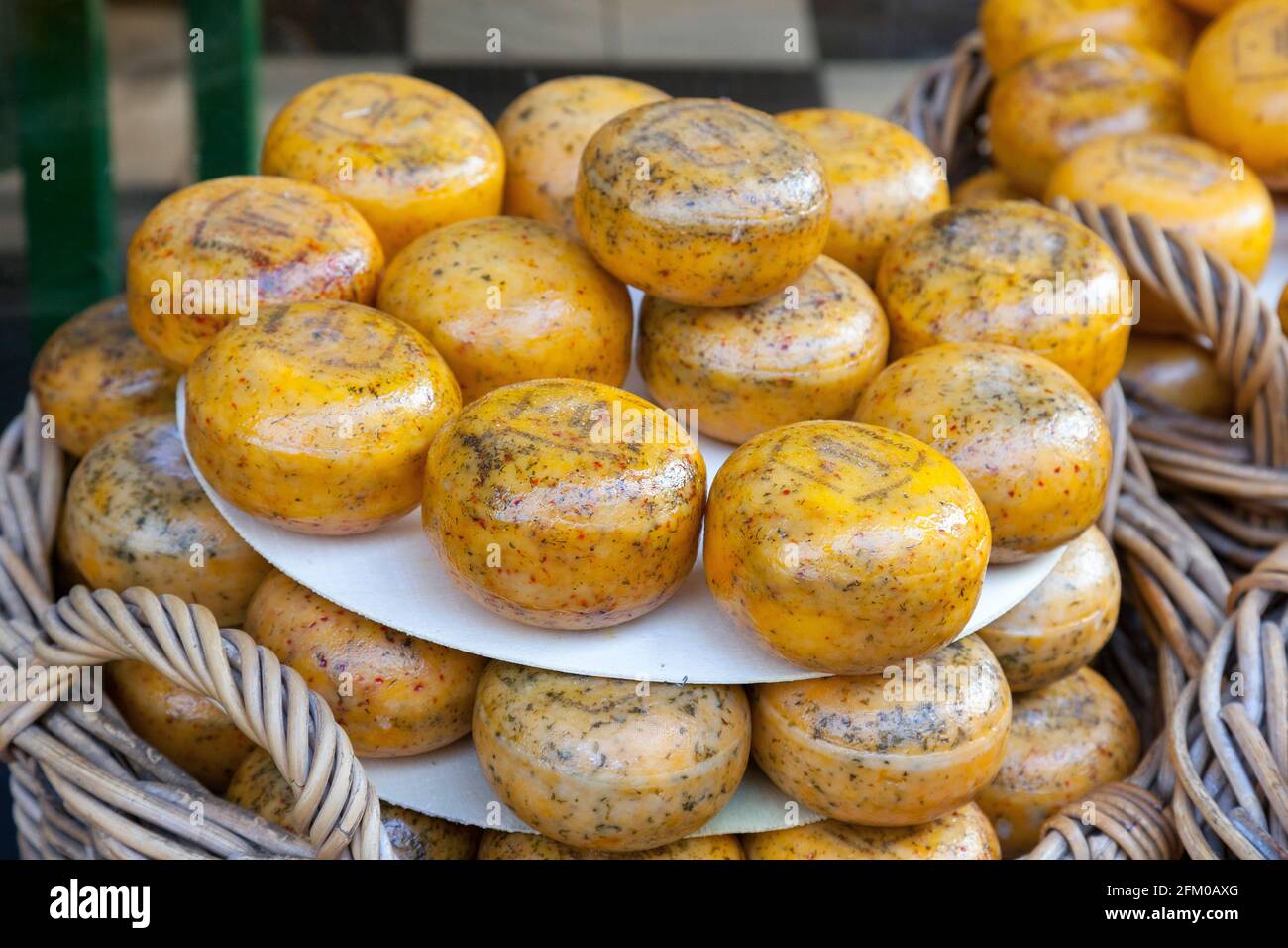 Round shaped smoked Gouda hard cheese in straw basket, Amsterdam, North Holland, The Netherlands Stock Photo
