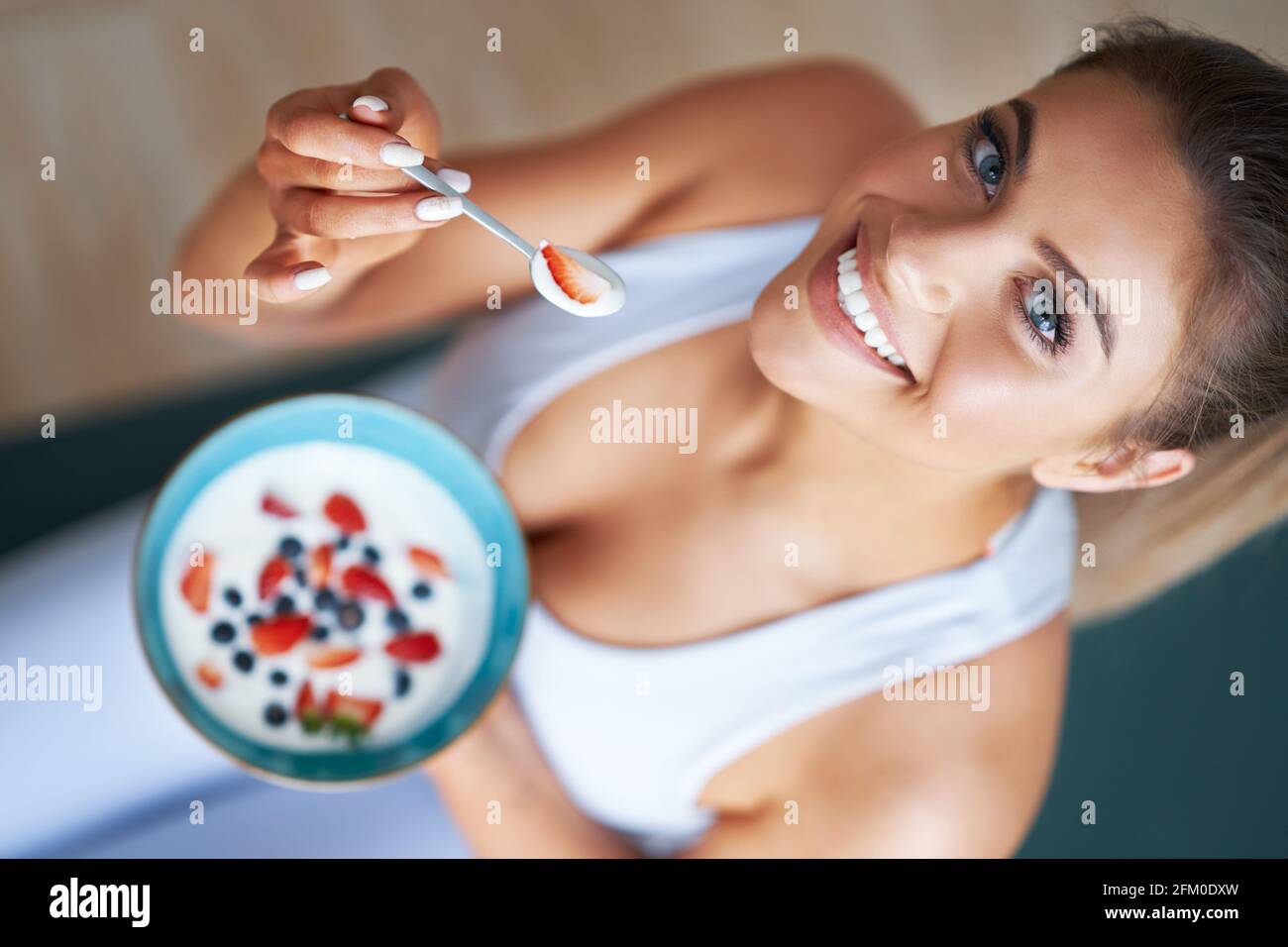 Portrait of beautiful hispanic woman eating yoghurt promoting healthy lifestyle Stock Photo