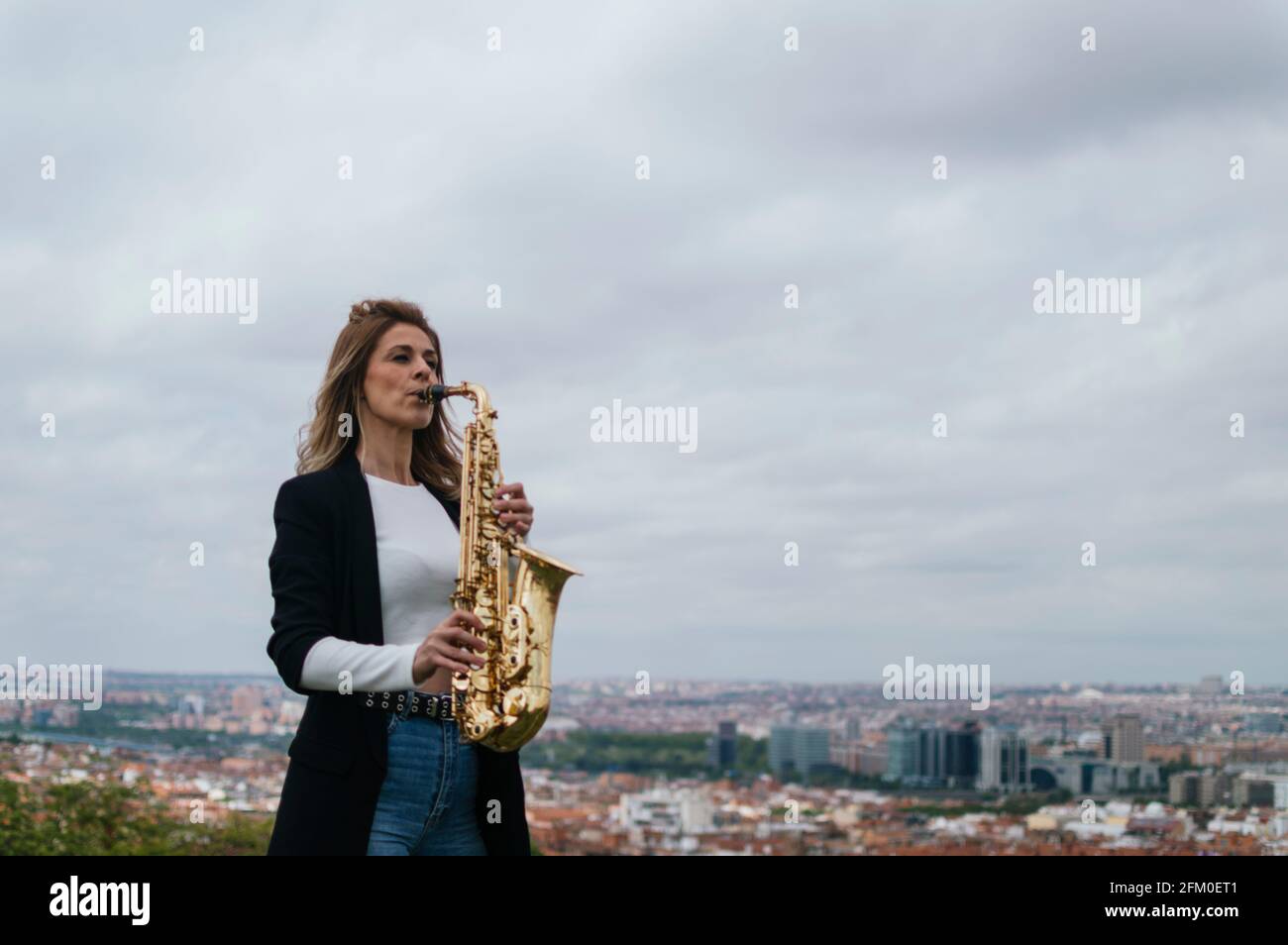 Young blonde girl playing the saxophone in a park Stock Photo