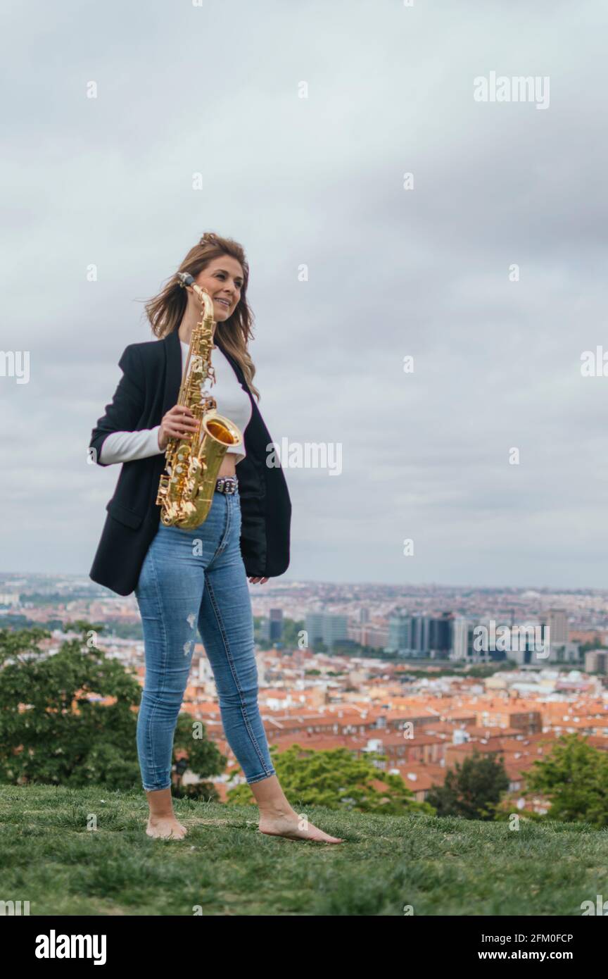 Young blonde girl playing the saxophone in a park Stock Photo