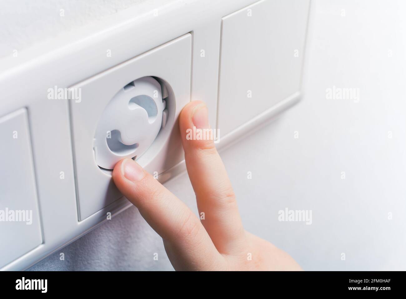 Two Child Fingers Touching A Wall Socket With Safety Plugs Prevent