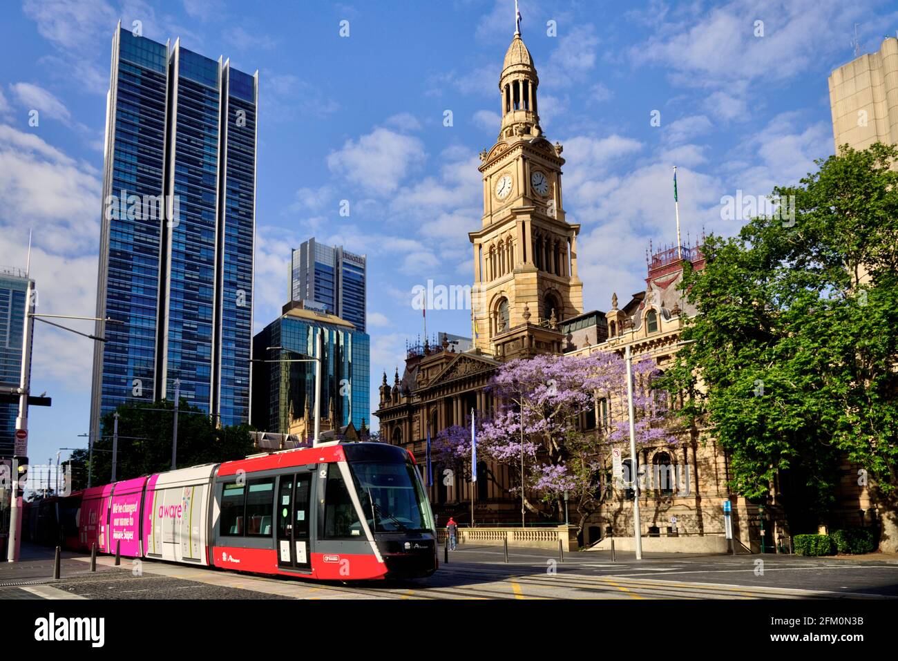 Light Rail electric transport system passing the front of Sydney Town Hall on George Street Sydney Australia Stock Photo