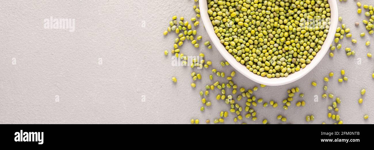 Legumes in bowl and scattered in the background, mung beans in a plate banner, top view, copy space Stock Photo