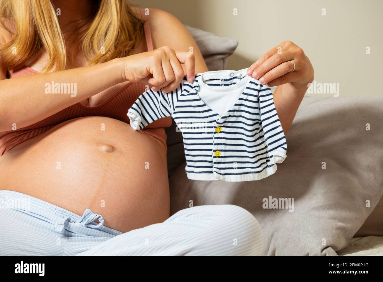 Pregnant woman play with tiny clothes for new baby Stock Photo
