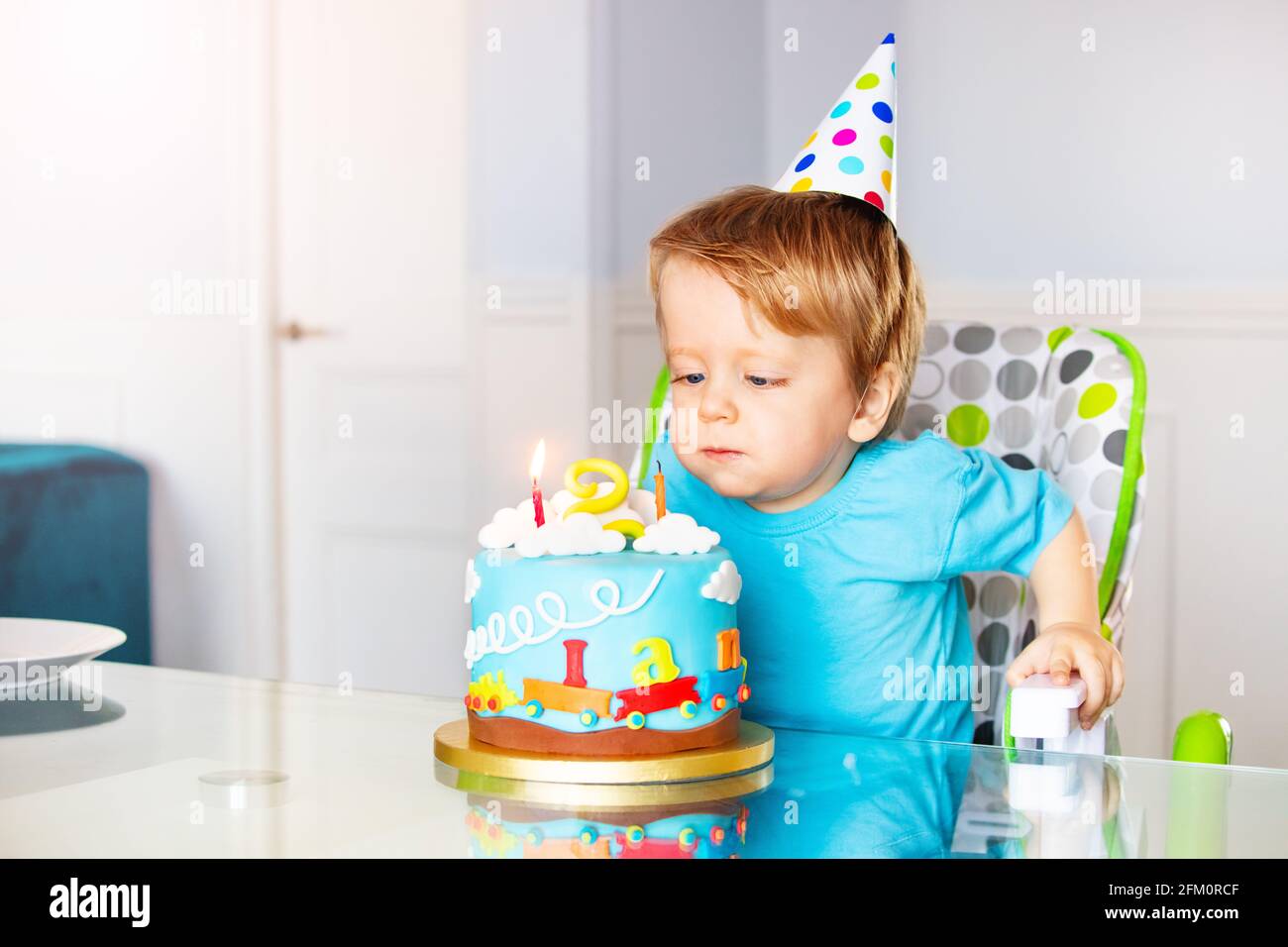 Toddler in high chair blow candles birthday cake Stock Photo Alamy