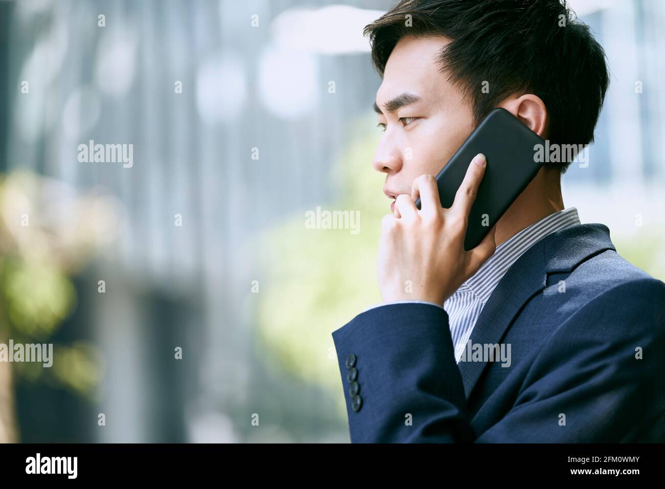 young asian businessman talking on cellphone outdoors Stock Photo