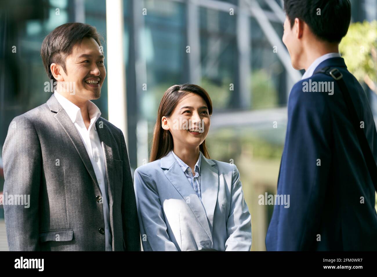 three asian business associates chatting in the street of downtown financial district in modern city Stock Photo