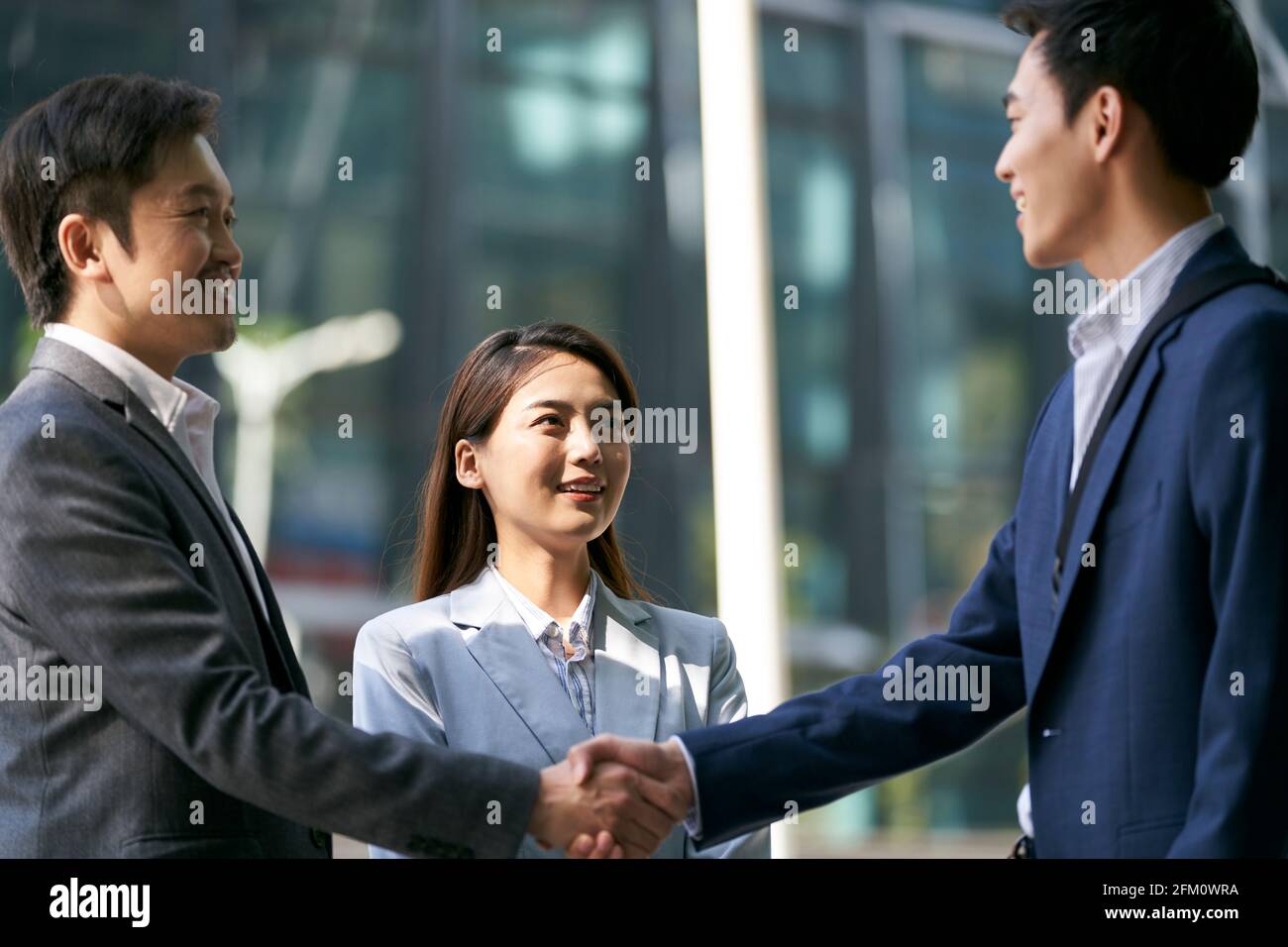 asian business associates meeting in the street in downtown financial district shaking hands Stock Photo