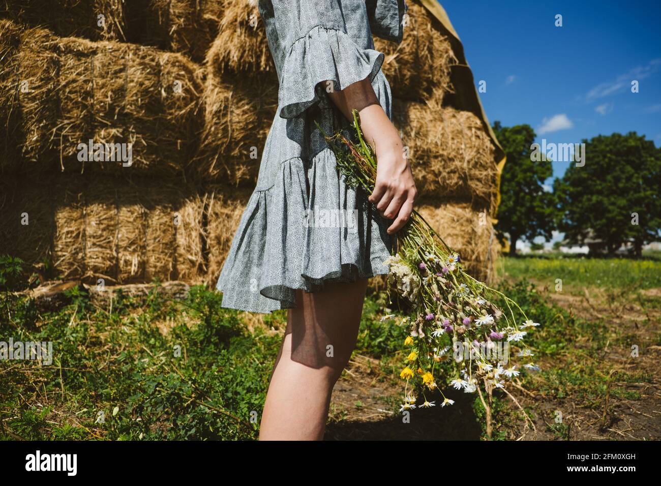 Young girl in rubber boots with flowers standing against the background ...