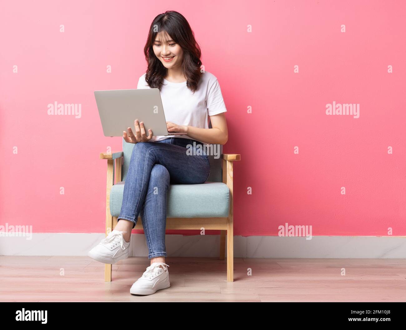 Asian woman sitting on sofa using laptop with happy expression Stock ...