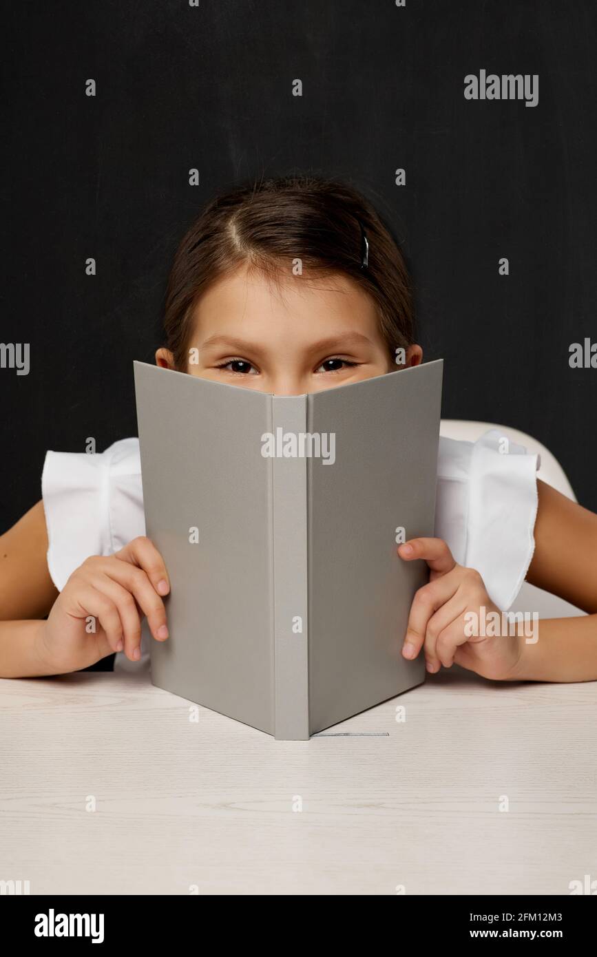 little child girl cover her face by the book Stock Photo Alamy