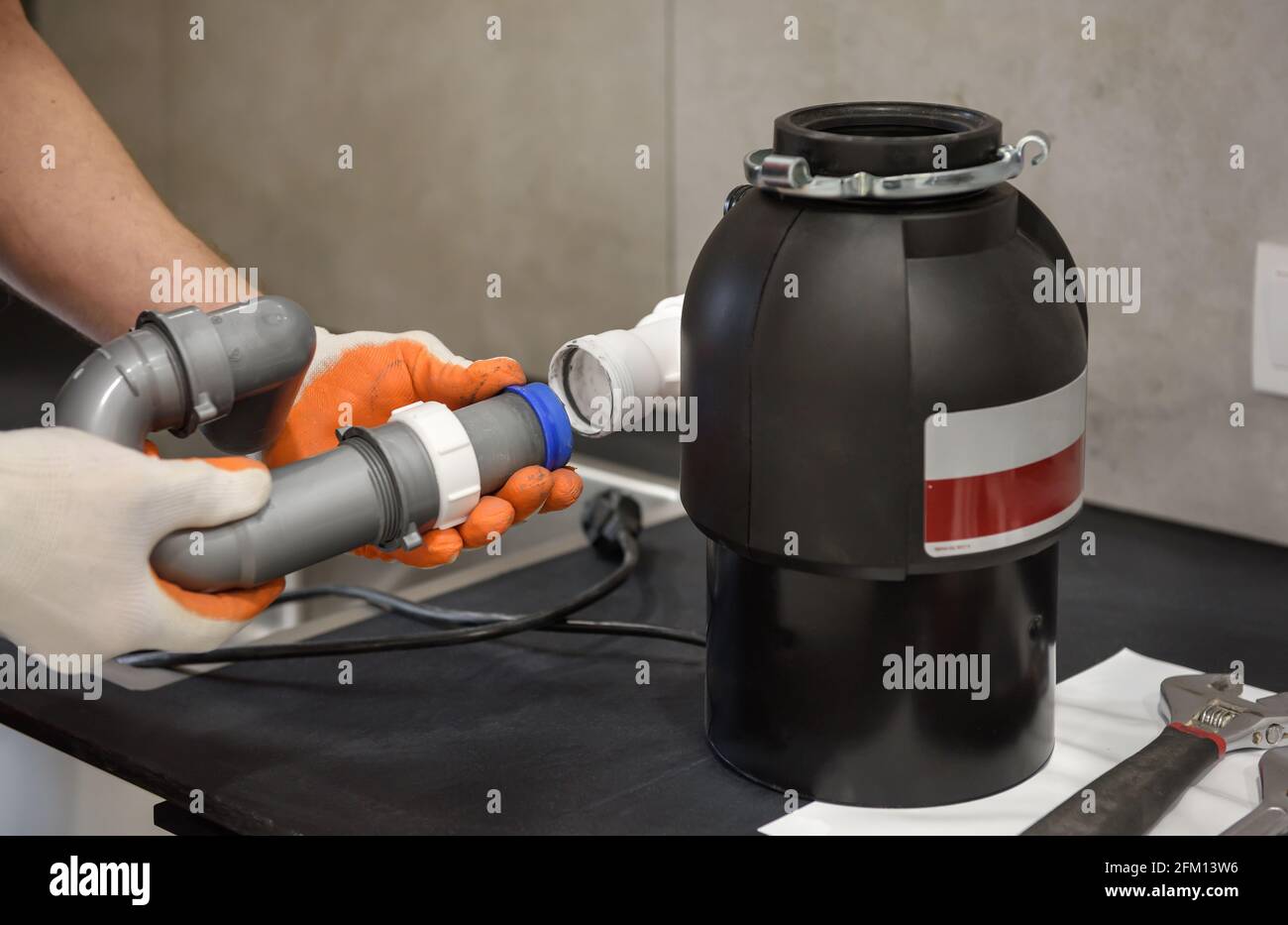A worker is installing a household waste shredder for the kitchen sink
