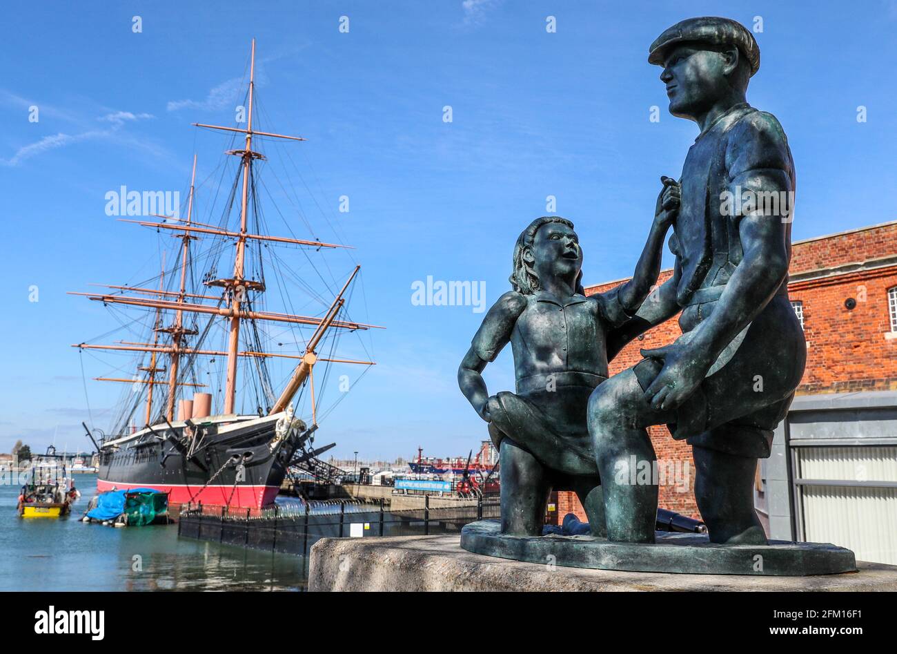 The Mudlarks statue, the Hard, Portsmouth with HMS Warrior in the background, Portsmouth, Hampshire, UK. Stock Photo