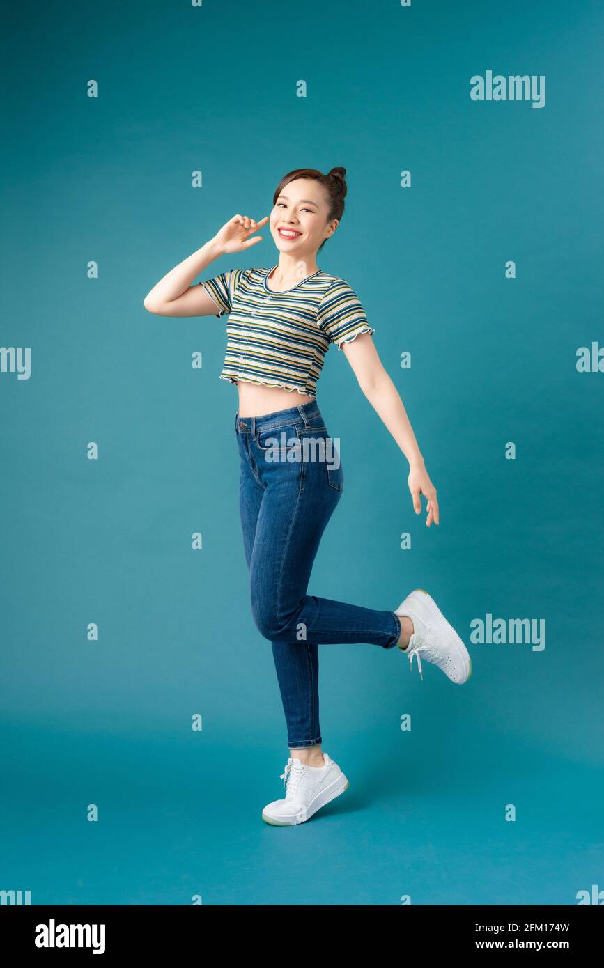 Full length portrait of a cheerful casual asian woman jumping isolated ...