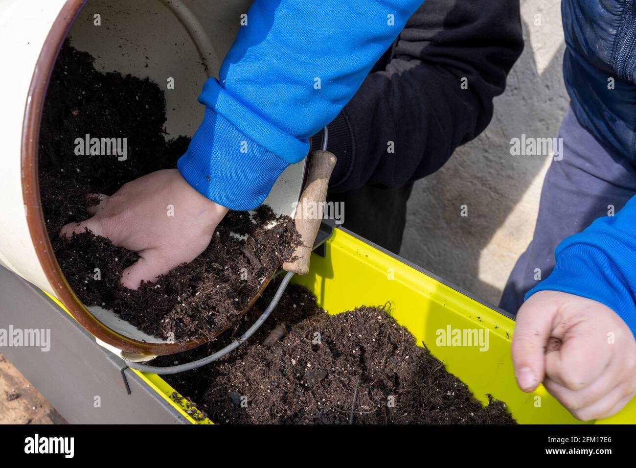 Little boy puts soil in balcony box to plant new vegetables Stock Photo