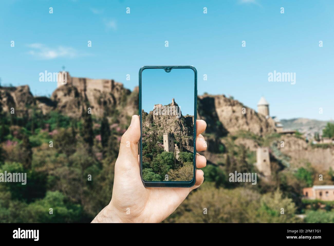 Georgia and Tbilisi landscape. A hand with a smartphone photographing the sights of Georgia and Tbilisi. Travel in Georgia and tourism concept. High quality photo Stock Photo